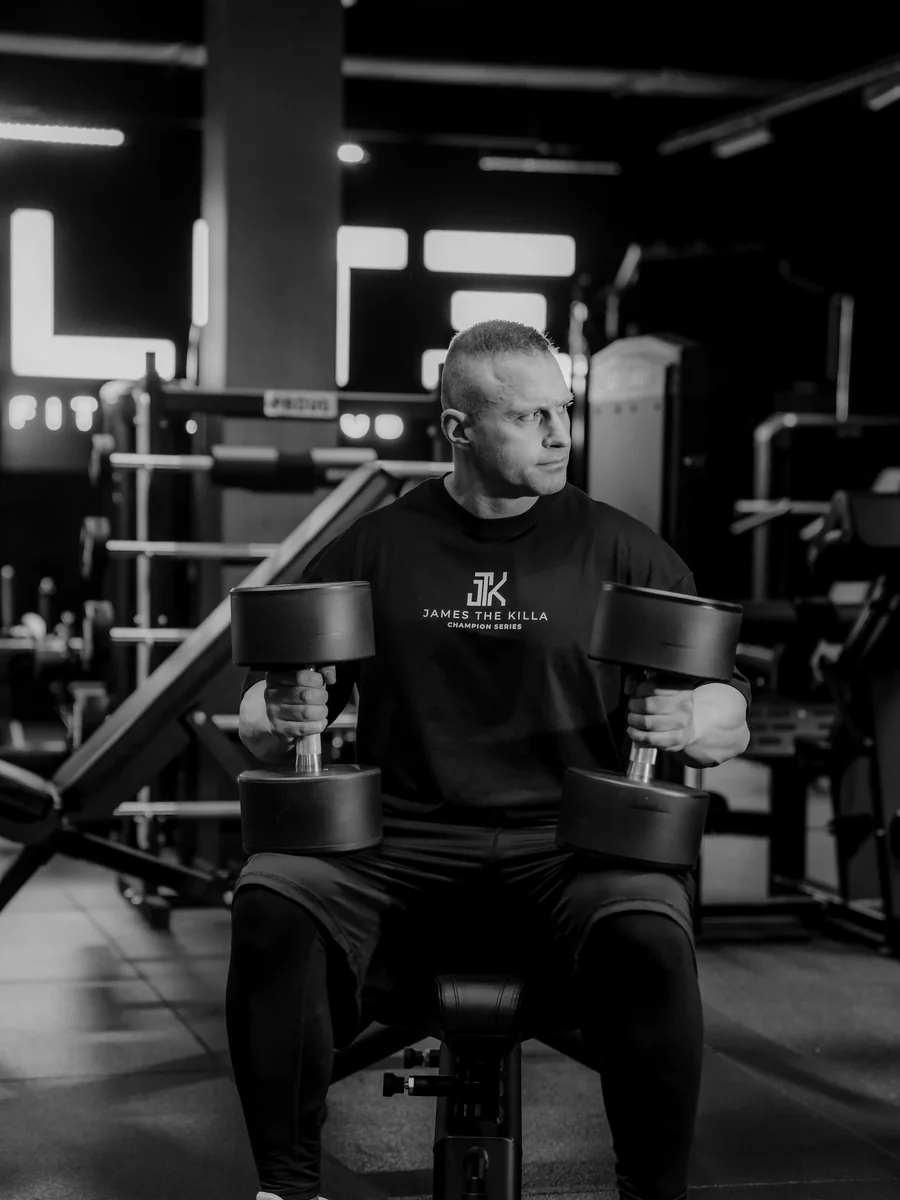 Jakub Kaszuba, trener personalny i Mistrz Świata IBFF 2020, z hantlami na siłowni
